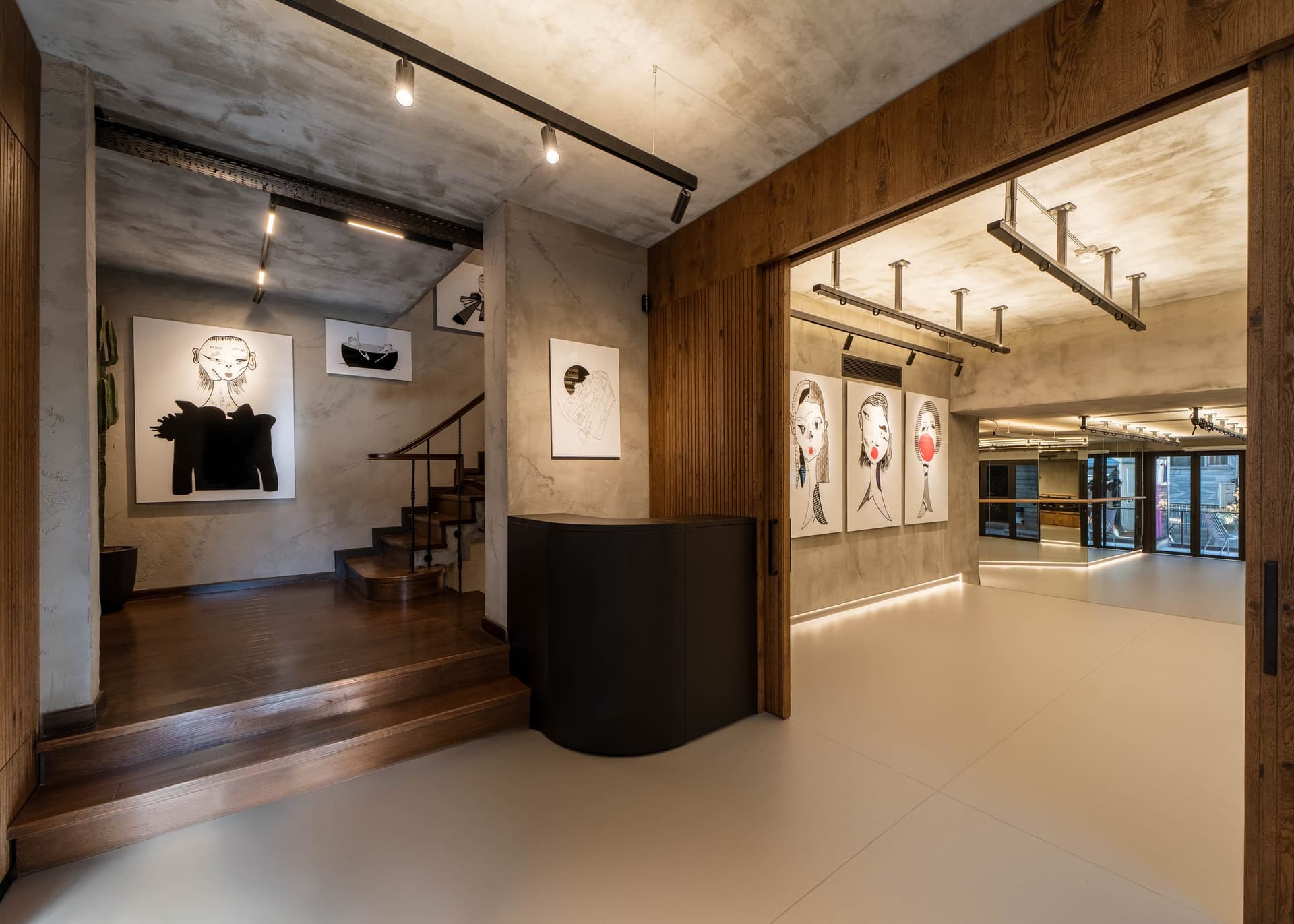 Entrance with a black reception desk, staircase and wall drawings under a wooden frame