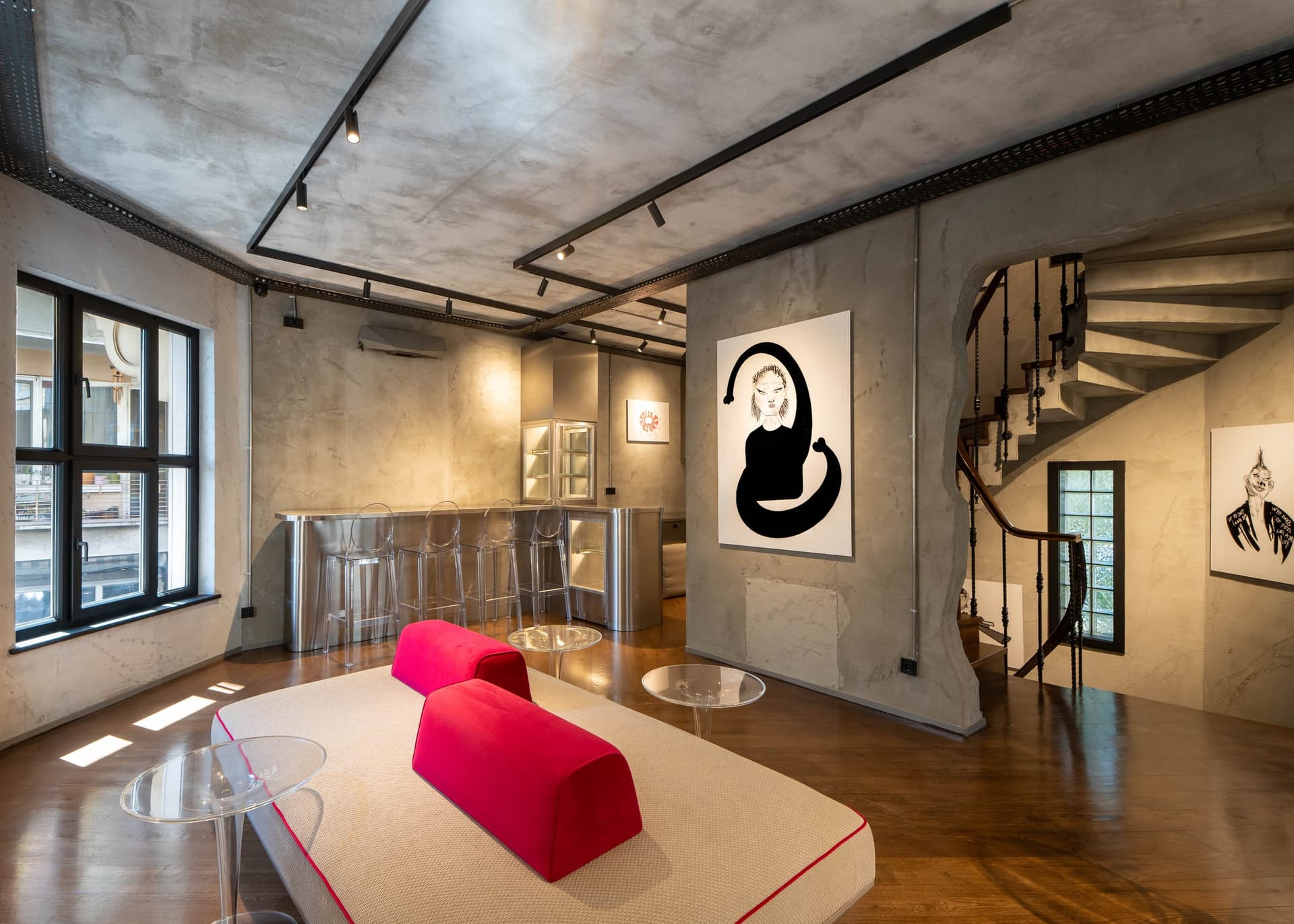 Lounge with a red sofa, drawings and a spiral staircase