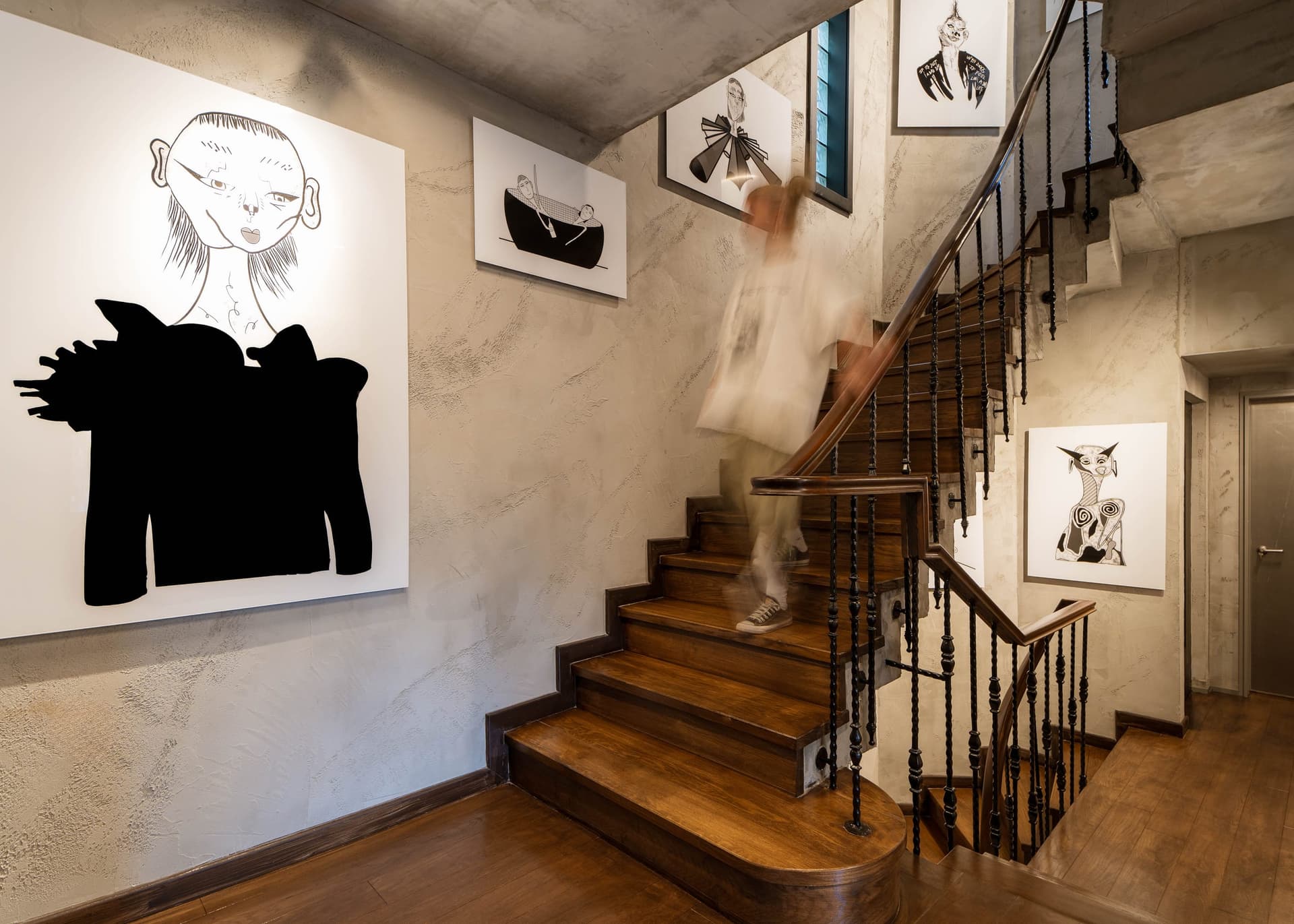 Wooden staircase with black-and-white drawings on the walls